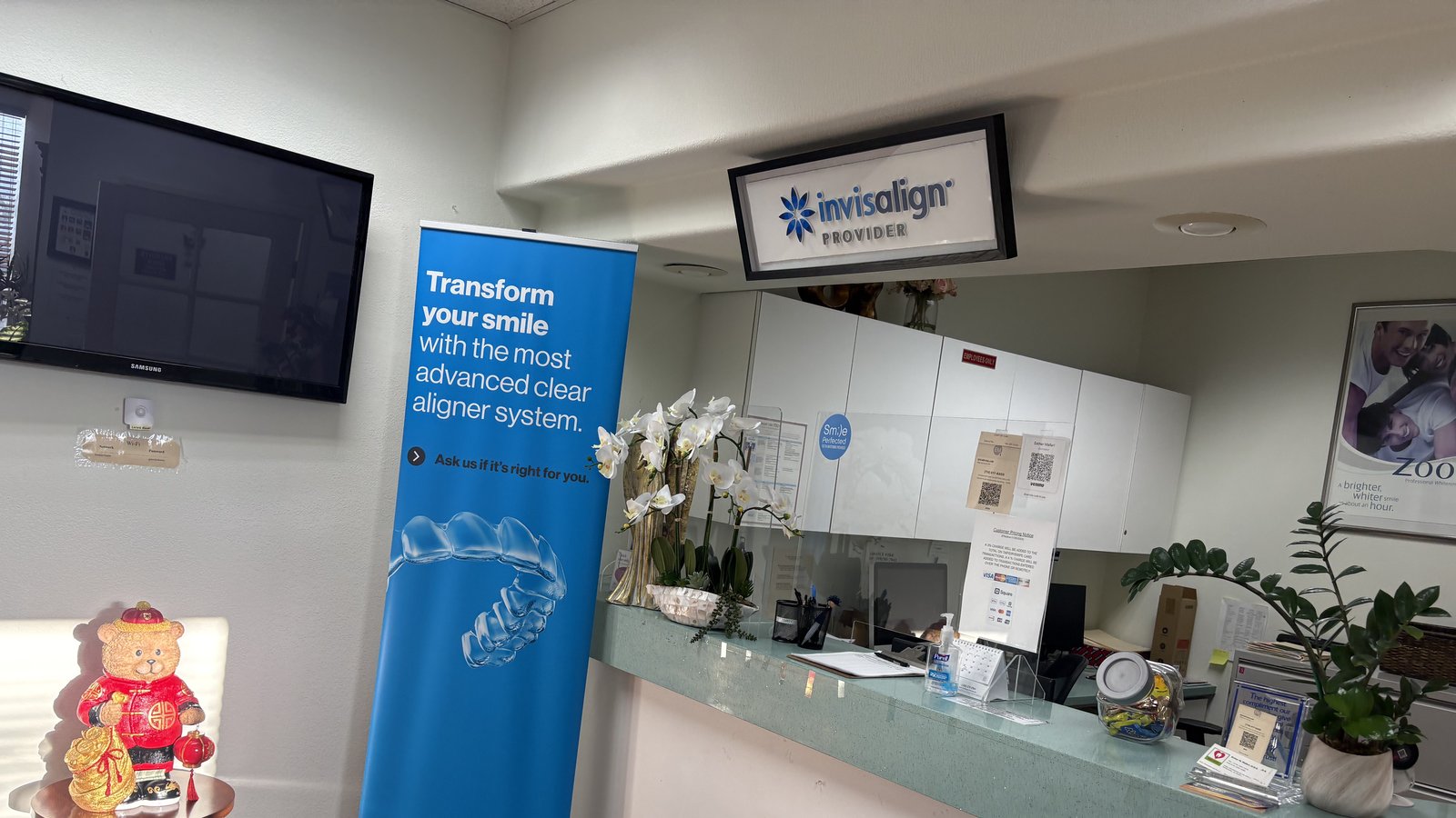The front desk at Dental Care of Torrance, showing the certified Invisalign Provider sign and a patient-information banner
